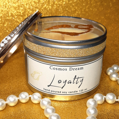 yellow Loyalty candle photographed with golden background and a pearl necklace